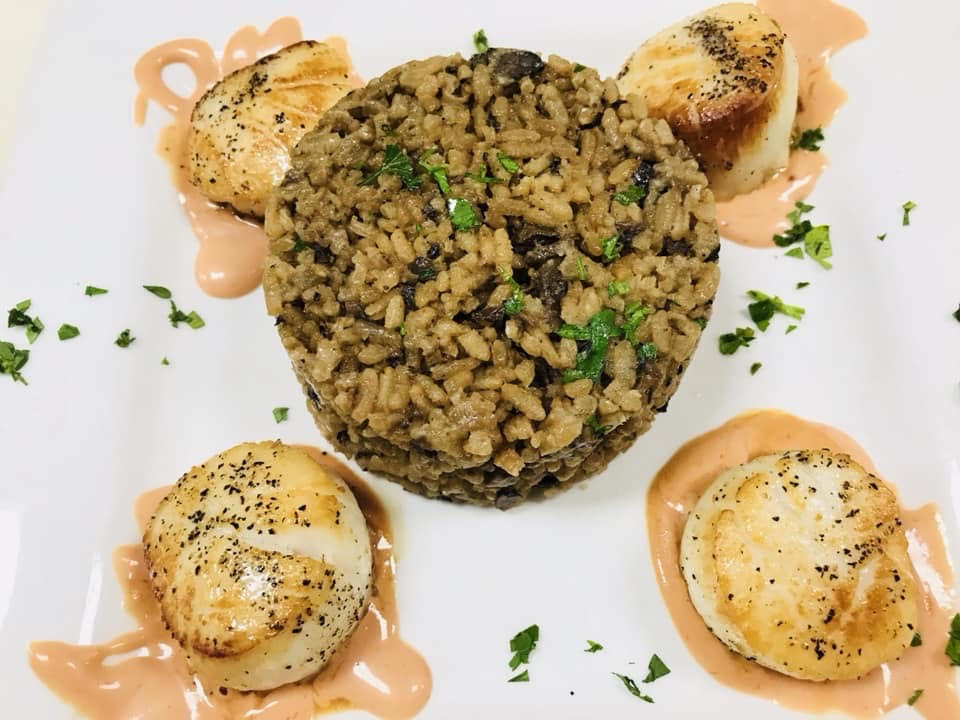 A plate with scallops, rice and sauce.