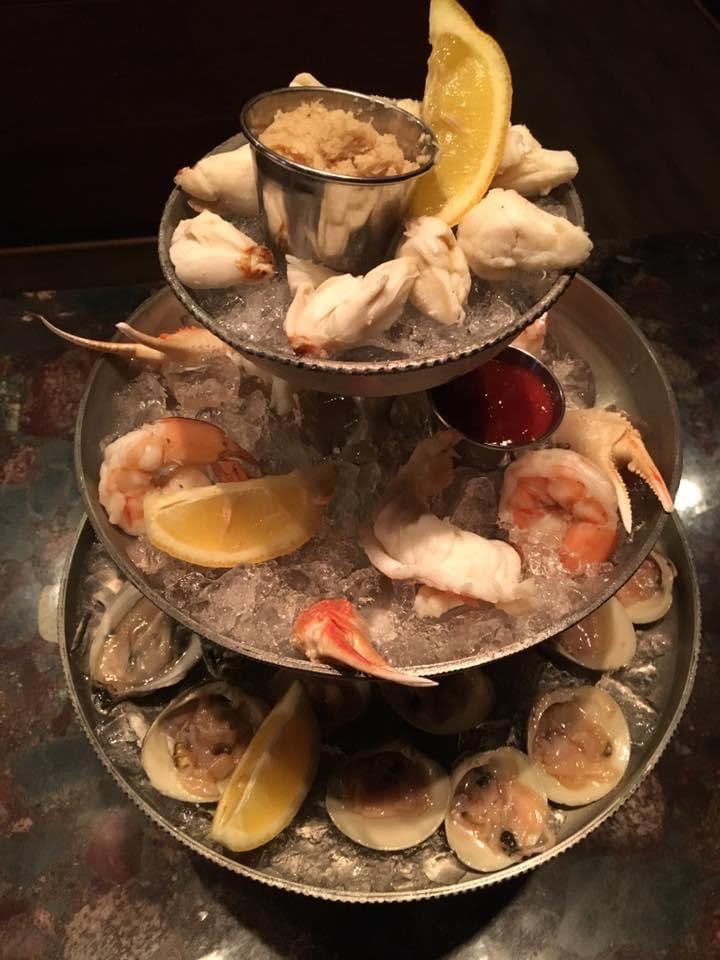 Three tiers of clams and oysters on a table.