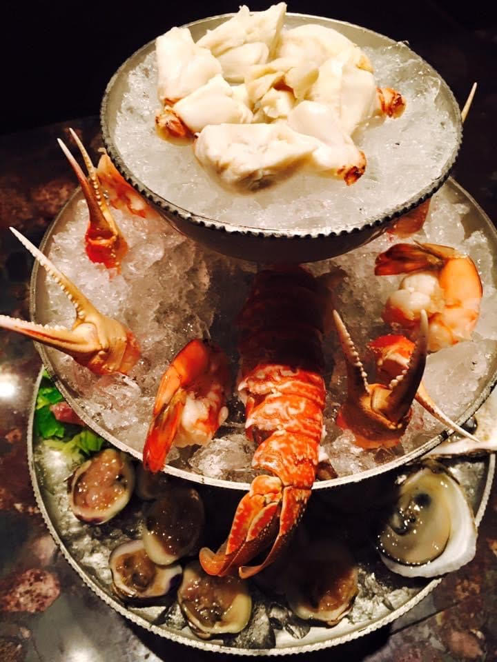 Three tiers of seafood on ice on a table.