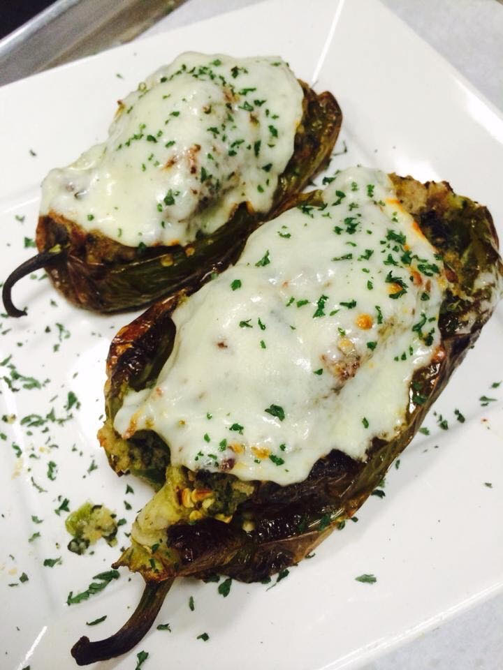 Two stuffed peppers with cheese on a plate.