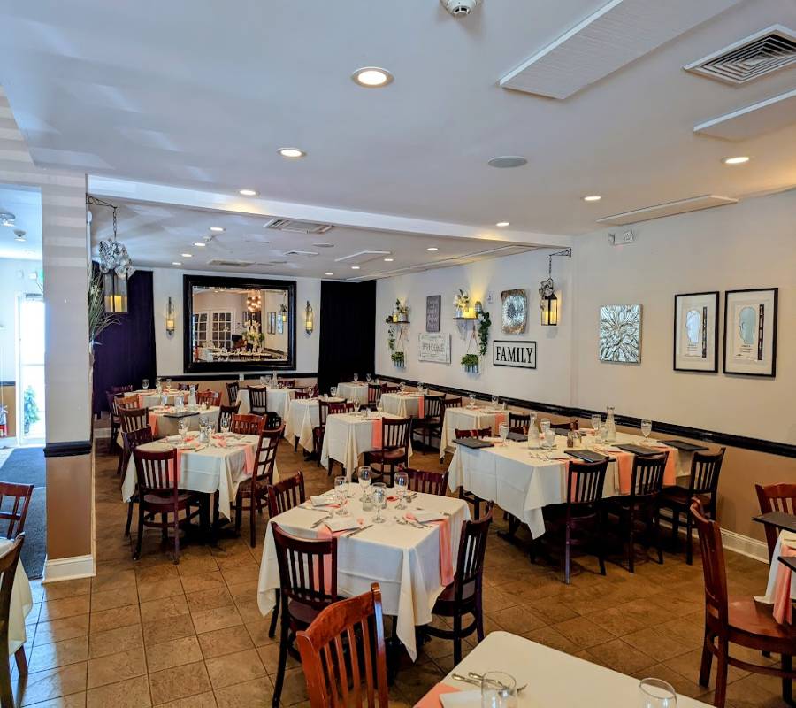 An empty restaurant with white tables and chairs.