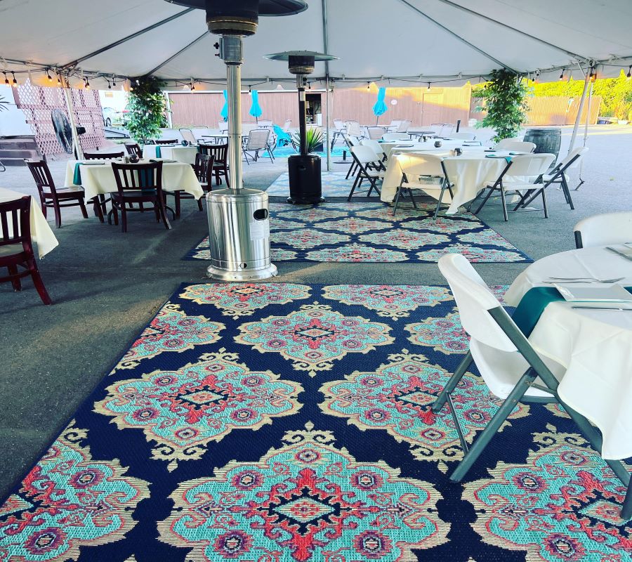 A tent with tables and chairs and a rug.